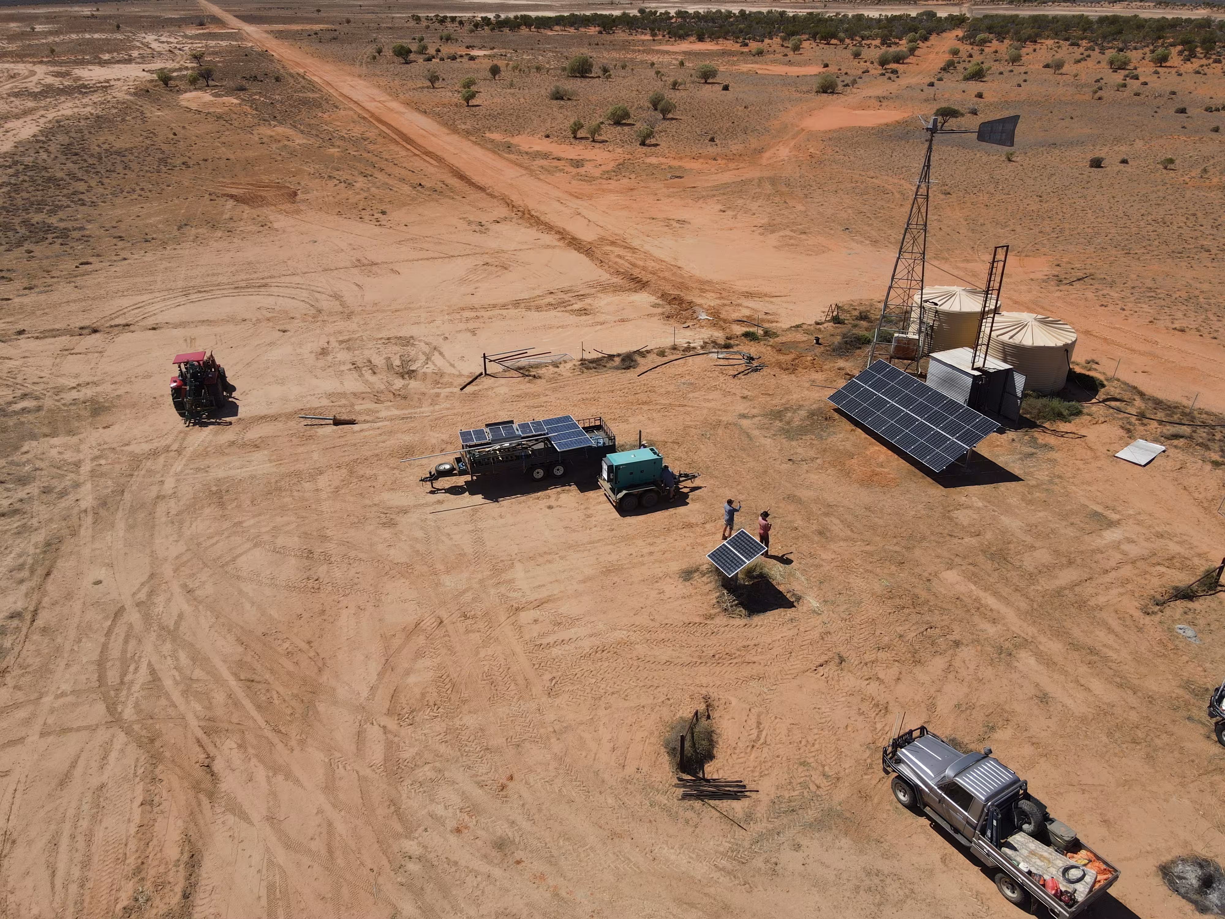 Aerial drone view of a RAMS remote outback solar pumping and off-grid power installation site featuring solar arrays, water storage tanks, service utilities, and fields tools on a rural property.