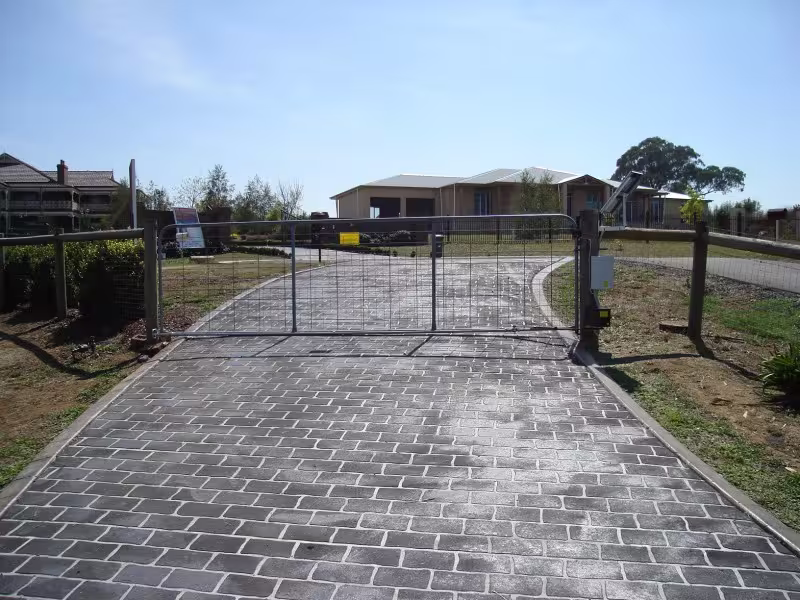 Solar powered automatic farm gate opener installed on a residential cobblestone driveway for secure property access.